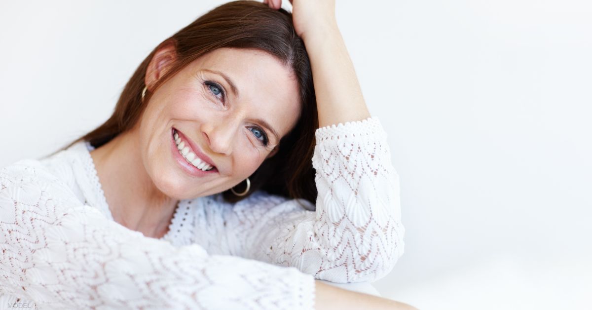 Woman is smiling while sitting on a couch (MODEL)